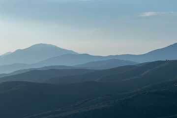 Fototapeta premium A view of the landscape, in which the mountain hills are in the morning haze of fog