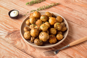 Plate with tasty baked potato on wooden background