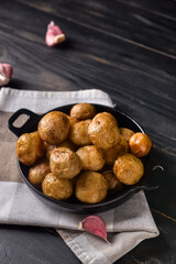 Frying pan with baked potato on dark wooden background