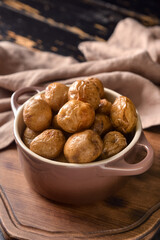 Pot with tasty baked potato on board