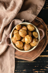 Pot with baked potato on wooden background