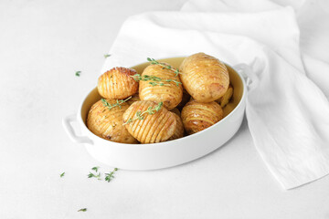 Dish with baked potato on light background