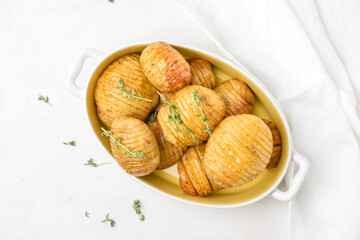 Dish with baked potato on light background