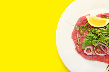 Plate with tasty veal carpaccio on color background