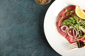 Plate with tasty veal carpaccio on dark background