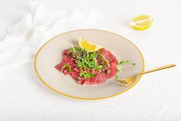 Plate with tasty veal carpaccio on light background