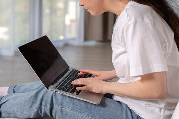 Caucasian woman looking in laptops screen and typing. Home interior. Close up view. The concept of online education and internet courses