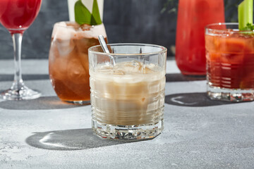 White russian cocktail is a cocktail made from coffee liqueur and vodka. Cocktail glass with spoon on vintage table with sunshine and long shadow. Classic cocktail collection.