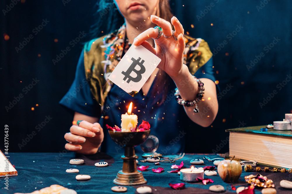 Wall mural the fortune teller shows a card with the bitcoin currency, and sets it on fire from the candle flame