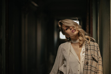Elegant calm blonde curly lady in white stylish blouse and tweed jacket looks into camera. Young...
