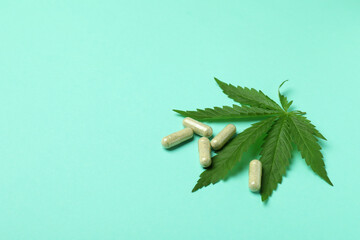 Cannabis leaf and pills on mint background