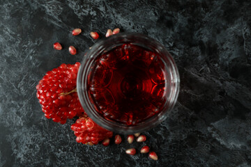 Glass of pomegranate juice and ingredient on black smokey table