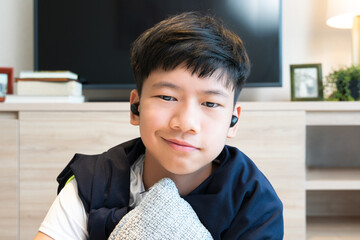Webcam video call portrait of young handsome Asian teenager boy with wireless earbuds, smiling, to...