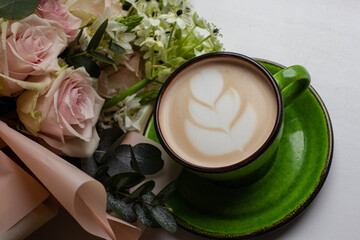 latte in nice green cup with latte art. morning coffee and flowers. roses bouquet