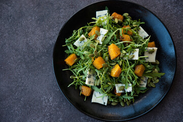 Arugula, blue cheese, pumpkin, pumpkin seeds, salad in a plate, top view