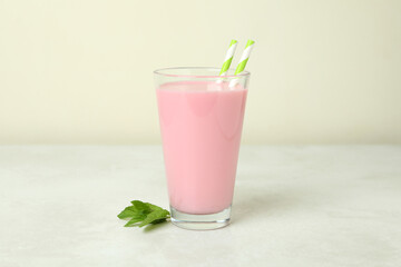 Glass of strawberry milkshake on white textured table