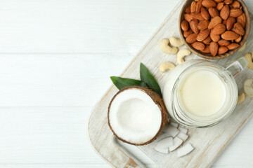Concept of vegan milk on white wooden background, top view