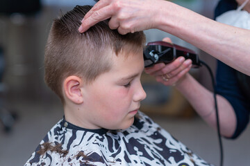 Cute kid have hair cut,professional barber doing haircut. Hairdress for children. side view portrait barbershop.Toned