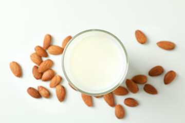 Glass of milk and almonds on white background
