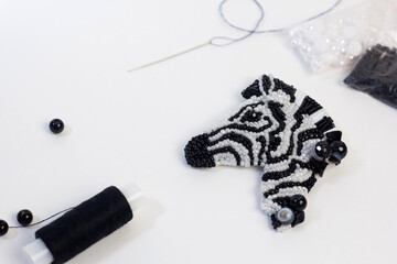 Handmade beaded zebra on white background. Sewed DIY present workshop. Jewelry designer making brooch with beads