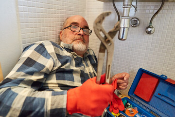 Installateur mit Rohrzange repariert Waschbecken Abfluss