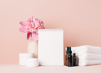Womens accessories cream oil various cosmetics clean blank notebook on a table with flowers. Beauty concept