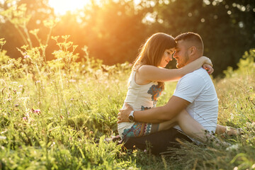 Fototapeta premium Couple lovers hugging and kissing in the park at sunset. Love, youth, happiness concept. 