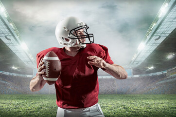 American football sportsman player with ball in action on stadium under lights of background. Sport, proud footballer in white helmet and red t-shirt ready to play.