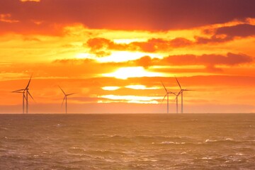 Renewable green electricity wind power generation offshore. Sunrise at decarbonization industry windmills business for regenerative energies. Clean energy renewables preventing climate change