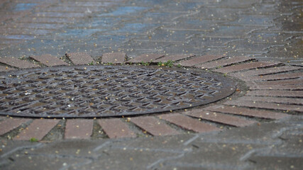 a metal hatch on the road during the rain . side view