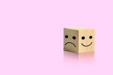 Wooden block with smiley face and bad face Positive and negative emotions in life isolated on pink...