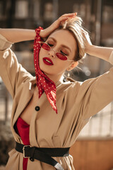 Pretty charming blonde woman with red lips poses outside. Attractive lady in colorful sunglasses...