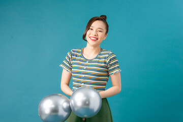 A woman holding silver color balloons against a blue background