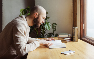 young bald man with a beard is sitting at a table