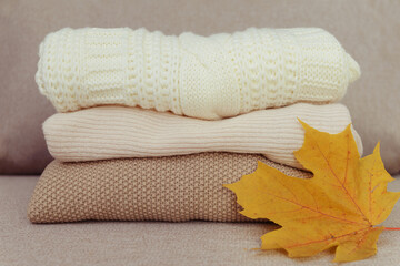 stack of sweaters,  an orange maple leaf on the couch