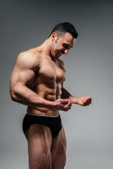 A young athlete bodybuilder poses in the studio topless, showing off his abs and muscles. Sport.