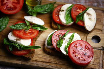 Caprese toast on a wooden board. Italian mood dish.