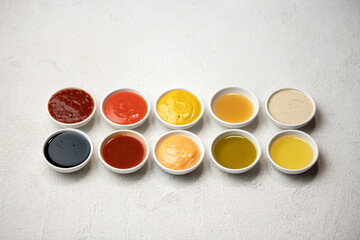 Big Set of colored sauces in Crockery. Different sauces, mayonnaise, mustard, soy sauce, oil and ketchup on white background. Top side view. Tasty food. Kitchen utensils.