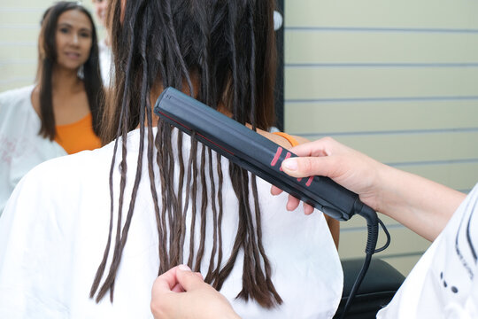 Young woman with dreadlocks. false dreadlocks on the curling iron.