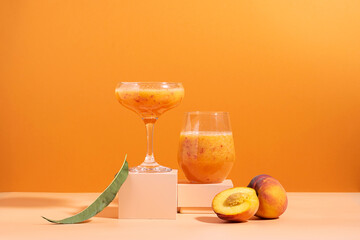 Juice fruit drink made from fresh ripe peach in a glass on a modern abstract podium orange...
