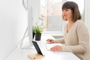 Beautiful professional businesswoman working with desktop computer in office. Photo of young woman sit indoors at home working on computer.