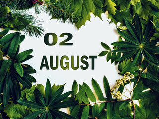 August 2, 2nd day of month. .Composition of natural green leaves with paper card. Summer month. Concept of Day of Year