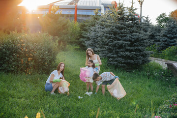 A group of girls with children at sunset are engaged in garbage collection in the park....
