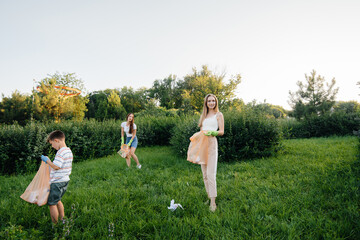 A group of girls with children at sunset are engaged in garbage collection in the park....
