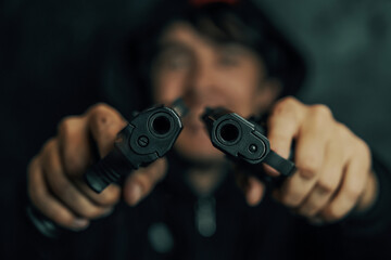 Close-up of two gun muzzles. Two pistols in man's hands are pointed at camera. Guy threatens with firearm. Criminal with weapon.