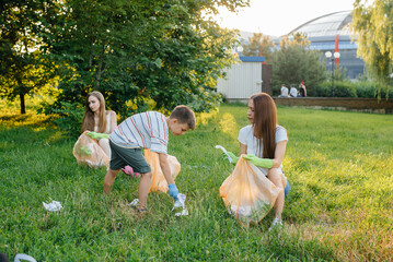 A group of girls with children at sunset are engaged in garbage collection in the park....