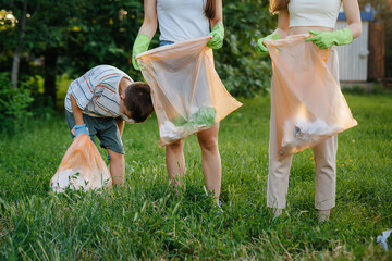 A group of girls with children at sunset are engaged in garbage collection in the park....