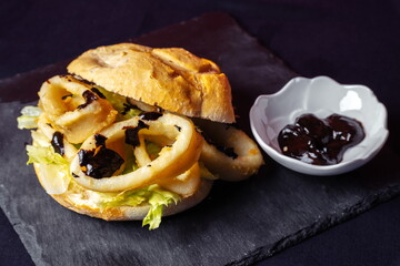 Sandwich with french fries and barbecue sauce on black background