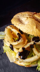 Sandwich with french fries and barbecue sauce on black background