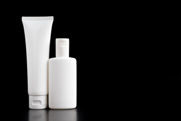 White tube and bottle of toothpaste or cream isolated on black background.white shadows blur on the floor